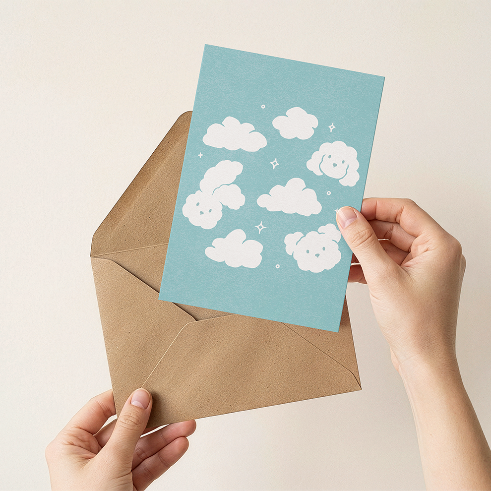 Hand holding a blue card with cloud animal designs and a brown envelope on a beige background