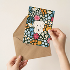 Hand holding a card with a dog illustration and floral design, placed inside an open brown envelope.