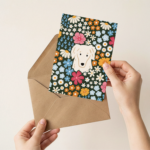 Hand holding a card with a dog illustration and floral design, placed inside an open brown envelope.