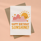 Greeting card with sun and cloud design and 'Happy Birthday Sunshine!' text on a peach background