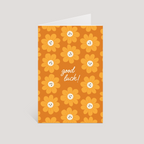Greeting card with yellow flowers and 'good luck!' text on an orange background