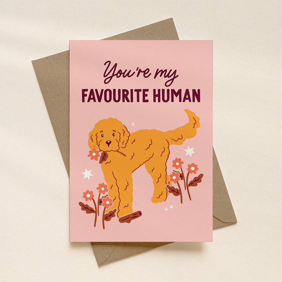 Greeting card with a dog illustration and text 'You're my favourite human' on a pink background.