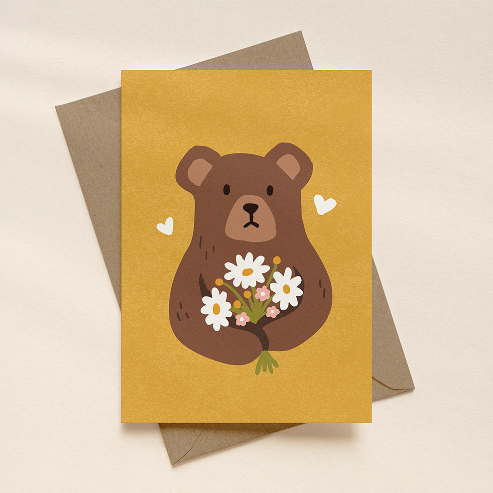 Greeting card with a bear holding flowers and a brown envelope on a beige background