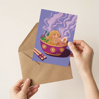 Illustrated card with a girl in a bowl of ramen, held over a brown envelope.