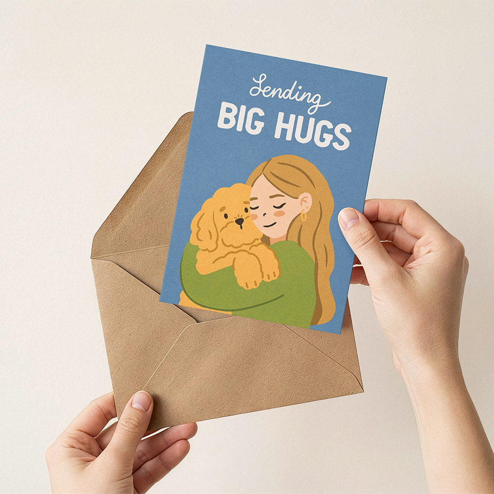 Card with illustration of a person hugging a dog and text 'Sending Big Hugs' held by hands with an envelope.