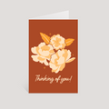 Greeting card with floral design and 'Thinking of you!' text on a brown background